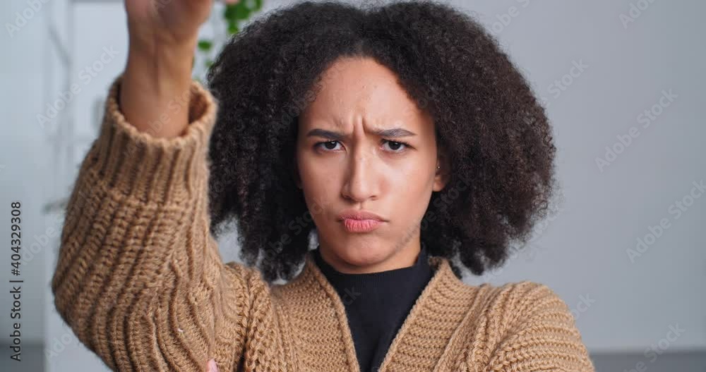 Portrait of lonely offended afro american woman says no frowning eyebrows waving says no shows dislike puts thumbs down expresses negative attitude confident stance prohibits, sad female face close up Portrait of lonely offended afro american woman says no frowning eyebrows waving says no shows dislike puts thumbs down expresses negative attitude confident stance prohibits, sad female face close up