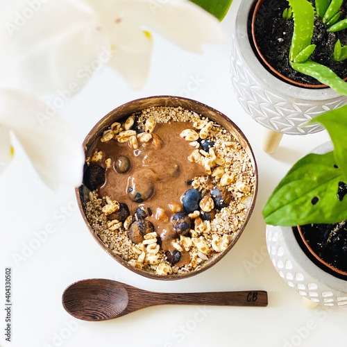 Porridge in einer Kokosnussschale mit Toppings, Heidelbeeren, Kelloggs, Haselnussmus photo