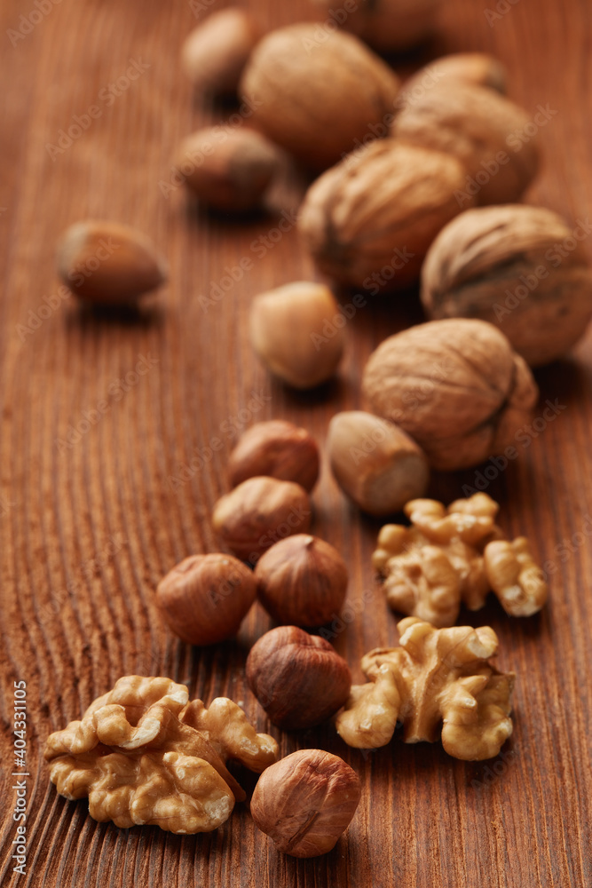 Walnuts and hazelnuts. Still life from whole nuts and kernels on brown textured wooden background. Selective focus on kernels Walnuts and hazelnuts. Still life from whole nuts and kernels on brown textured wooden background. Selective focus on kernels