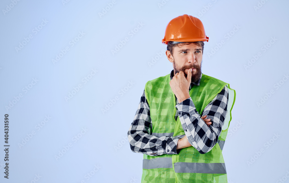 construction worker in orange hard hat on blue background and plaid shirt reflective vest