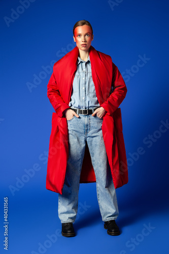 Fotografija Confident female model in baggy clothes against blue background