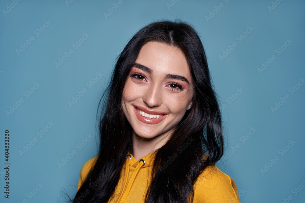 Smiling cute stylish cool gen z teen girl, happy asian ethnic zoomer teenager pretty face wearing hoodie looking at camera isolated on blue background. Close up headshot portrait. - obrazy, fototapety, plakaty 
