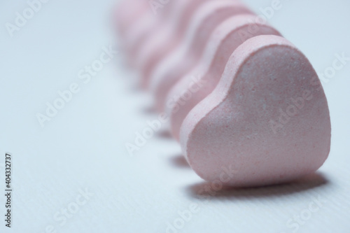 Φωτογραφία High Key image of row of pink hearts on white background.