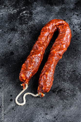 Spanish chorizo pork cured sausage. Black background. Top view