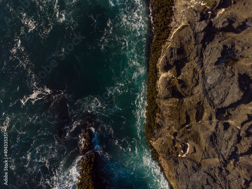 Aerial top view of fantastic rocky coast in the arms of the ocean waves. Wallpaper design. Amazing landscape. View from above.