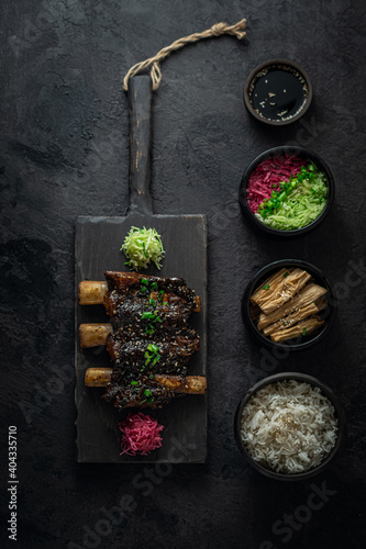 Braise beef short ribs, asian style with rice and radish, dark photo, flat lay