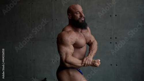 strongman with muscular body is posing for camera in studio, demonstrating figure photo