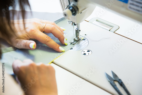 Woman hands with fabric at sewing machine