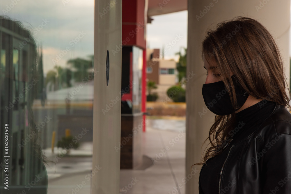 Fototapeta premium Beautiful woman in the city with black face mask for protection from contagion by Coronavirus, Covid-19