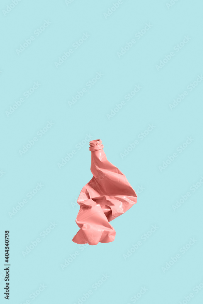 Fotografie Pink plastic  bottle on a blue background, squashed and ready for recycling
