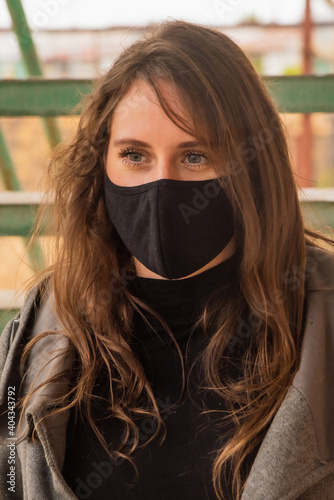Beautiful woman in the city with black face mask for protection from contagion by Coronavirus, Covid-19