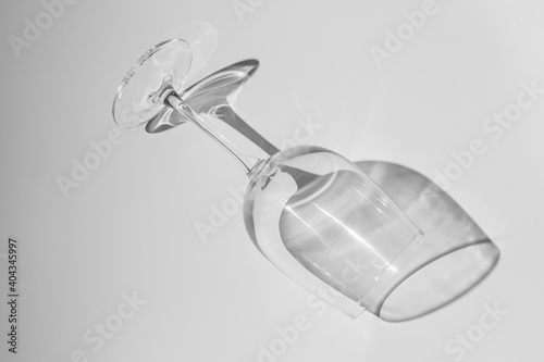 Wine glass lies on white background. Glass with hard shadow on white table.