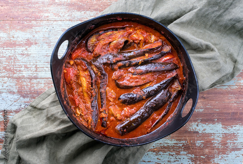 Modern style slow cooked Persian lamb eggplant stew khoresh bademjan served as close-up in a Design pot on a wooden board with copy space  photo