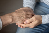 Crop close up of elderly father and adult son hold touch hands showing love and care in family relations. Loving man support comfort stressed unhappy mature dad, feel grateful and thankful.