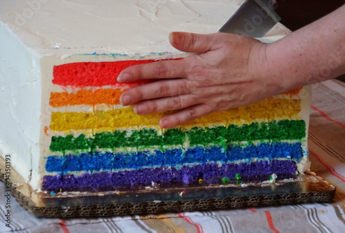 Cutting a beautiful rainbow cake on top of the table
