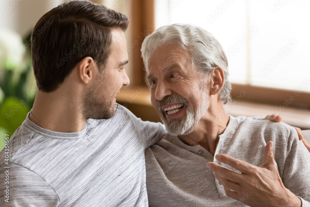 Close up of smiling mature 70s Caucasian father and grownup son talk and chat on vacation at home. Happy old senior man dad and adult child have fun enjoy family weekend. Bonding concept. Close up of smiling mature 70s Caucasian father and grownup son talk and chat on vacation at home. Happy old senior man dad and adult child have fun enjoy family weekend. Bonding concept.