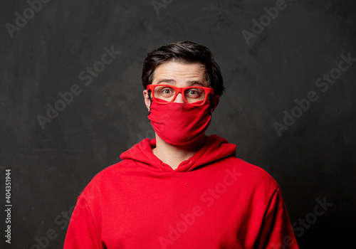 guy in red sweatshirt and face mask on dark background