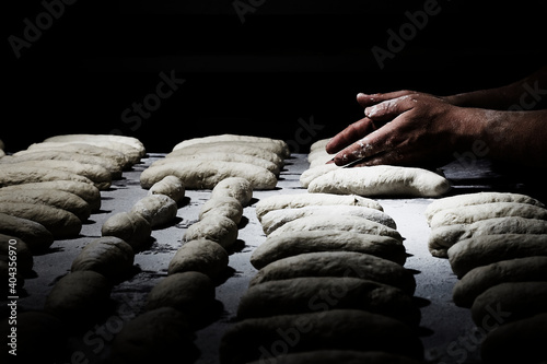 Hand of pastry chef or baker while preparing the dough for pizza