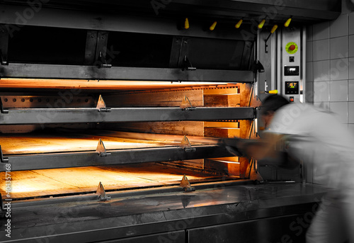 Bakery interior of baker oven with man taking bread