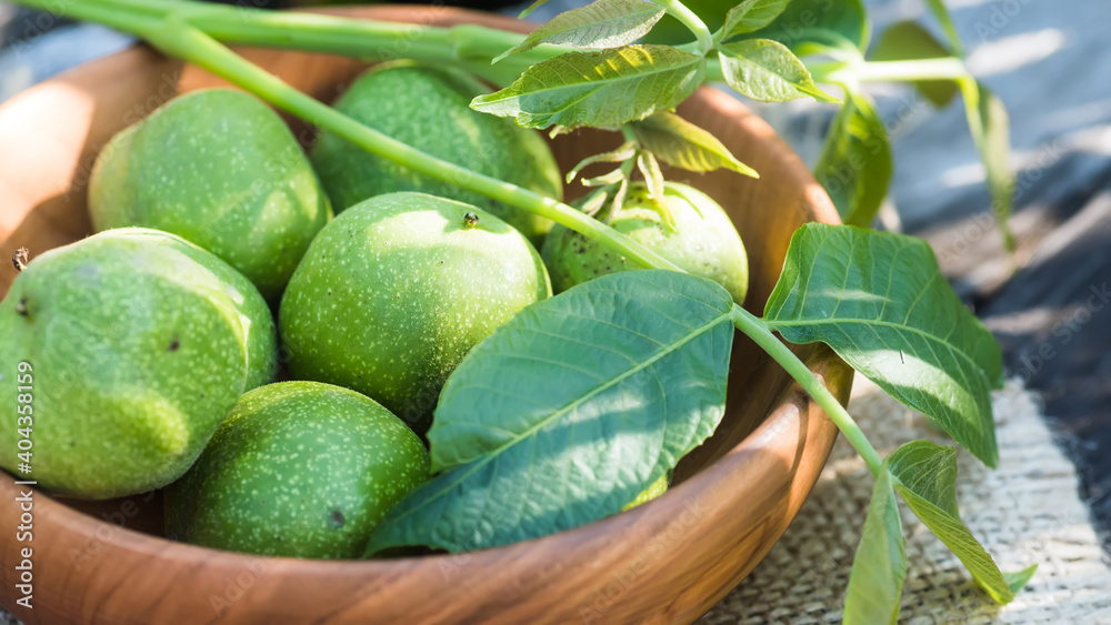 Obraz premium ingredients for tincture of green walnuts in a wooden ecological plate without chemicals. zero waste. Still life of nuts, wooden utensils.