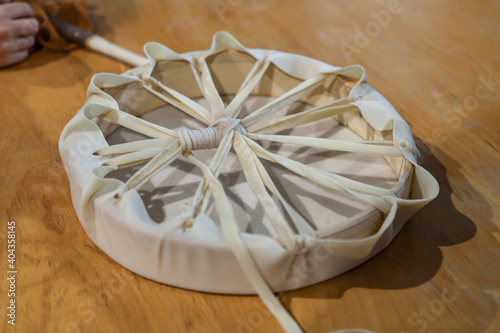 Close up from above of a recently finished tambourine or hand drum made with wood and leather lying on a table during a native drum workshop.  photo