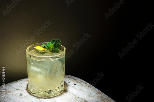 close up mojito cocktail, glass with ice mint and lemon, white table