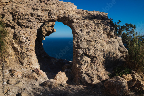 Natural stone arch with view to the ocean on a cliff of the natural park 'Serra Gelada' in Albir, Spain