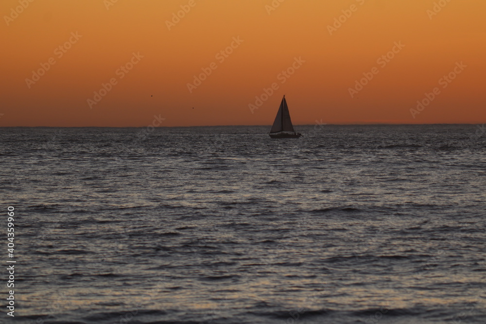 Beautiful sky with sailboat in the distance during sunset at the sea