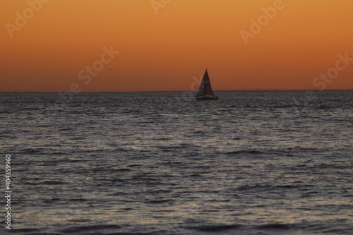 Beautiful sky with sailboat in the distance during sunset at the sea