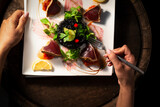 Woman's hands holding a fork over a plate with grilled tuna and black rice