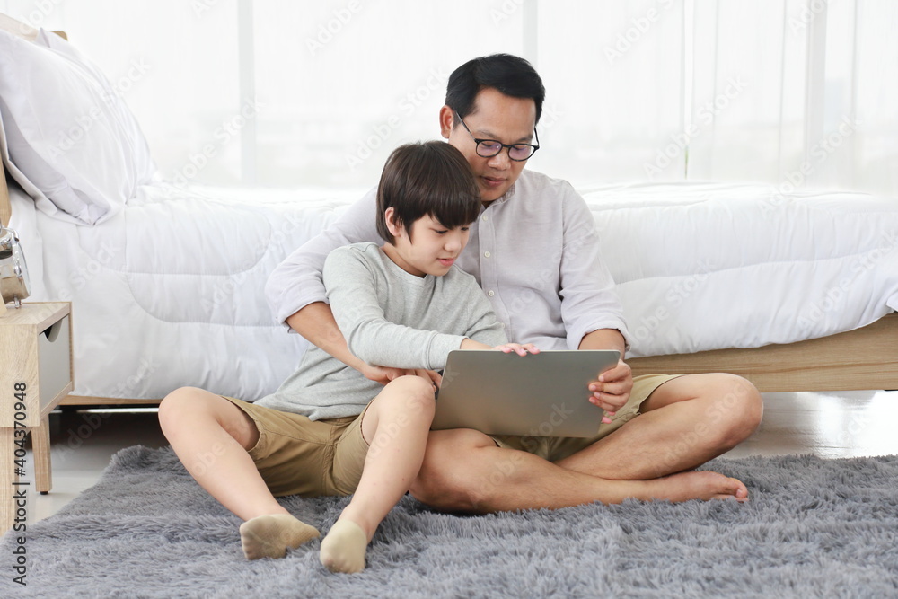 Asian father teaching homework to his son in bed for homeschooling, distance learning and education concept Asian father teaching homework to his son in bed for homeschooling, distance learning and education concept