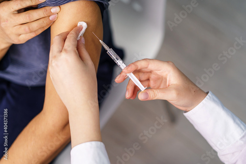 Vaccination healthcare concept - Hands of doctor or nurse hold a syringe and ampule preparing a shot of corona virus covid-19 hpv or flu vaccine for unknown patient arm - copy space close up