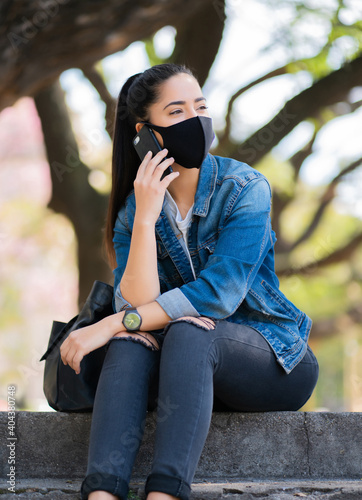 Young woman talking on the phone outdoors. © Mego-studio
