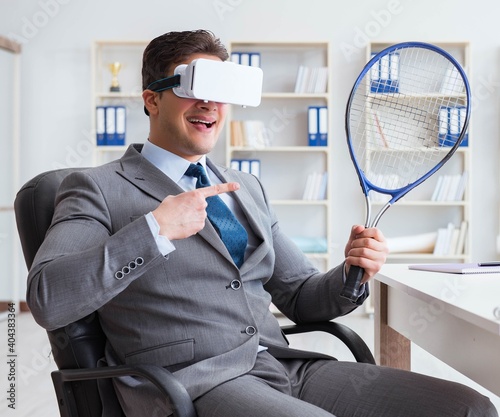 Businessman playing virtual reality tennis in office with VR gog