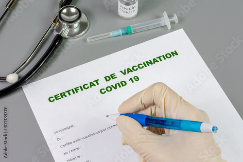 Main de docteur, remplissant un certificat de vaccination contre la Covid-19 photo