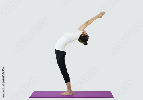 Young woman making yoga triangle pose on mat on white background 