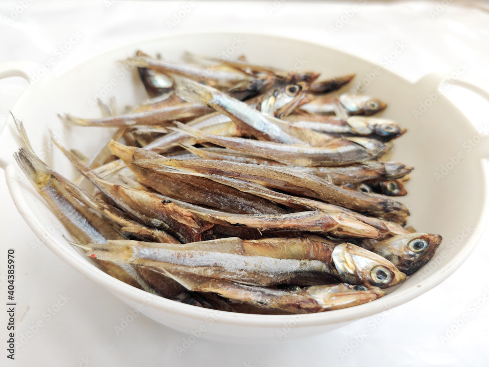 Dried Anchovy Fish decorated with herbs and lemons on a White Background,Selective Focus. Dried Anchovy Fish decorated with herbs and lemons on a White Background,Selective Focus.