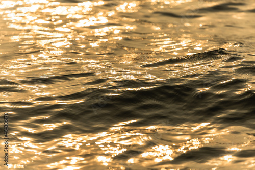 Water surface with moving wave of golden water reflecting .