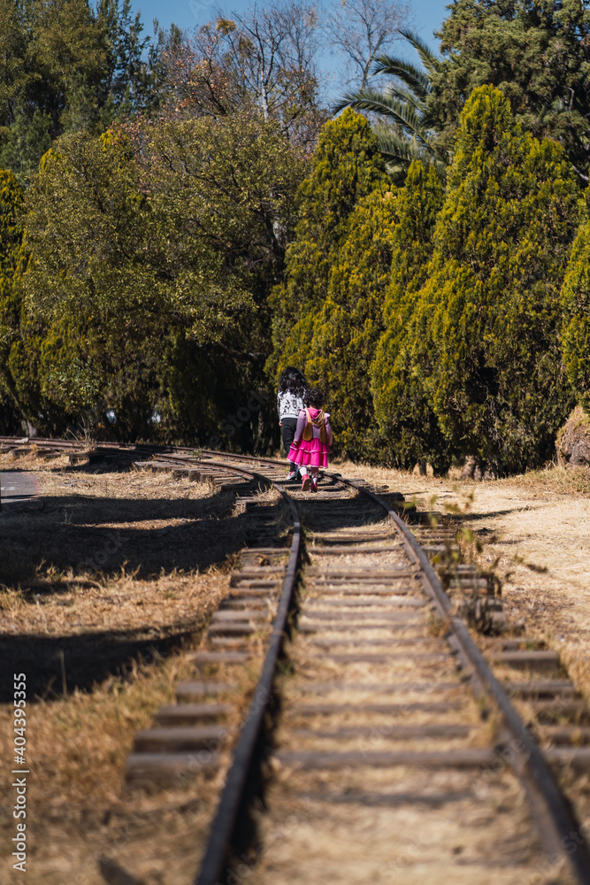 girls walking in the middle of train tracks concept visit to urban park, lifestyle