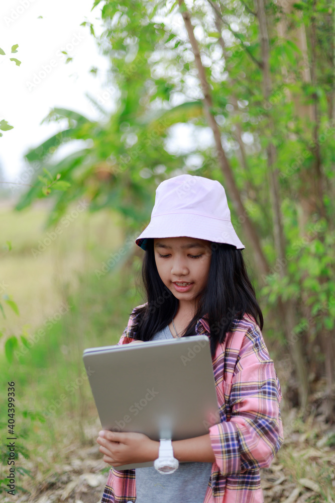 The little Asian girl holding tablet at the tropical farm, Little famer smile with happiness