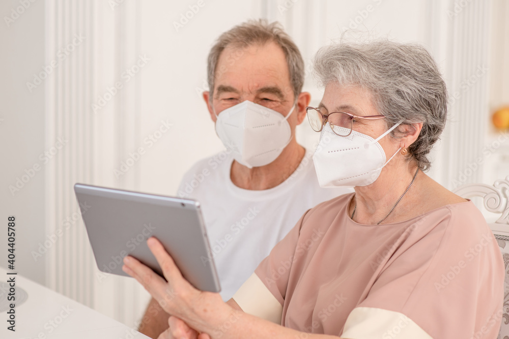 Senior couple wearing protective masks having video chat on tablet computer during the coronavirus epidemic