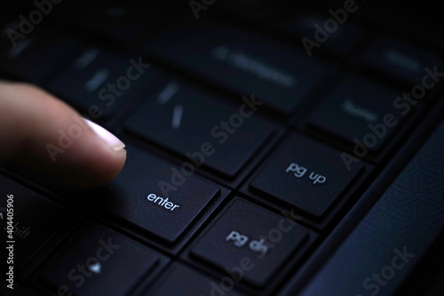 Human finger pressing enter button on keyboard © Sufian