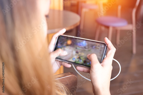 Asian girl are playing the mobile game with blurred on screen at home. The hand is touch screen for play game in the smartphone with clipping path.