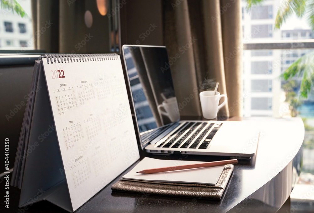 New normal concept: Close up desktop calendar 2022 on wooden desk in private office New normal concept: Close up desktop calendar 2022 on wooden desk in private office