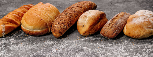 Food baking banner. Various types of fresh homemade bread on a gray concrete background. Horizontal shot