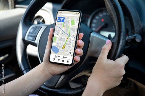 female hands driving car holding phone with navigator app screen