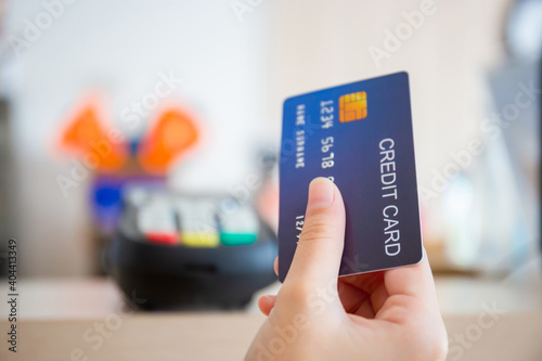 Hand of customer with credit card blurred credit card reader machine at bar counter, payment concept
