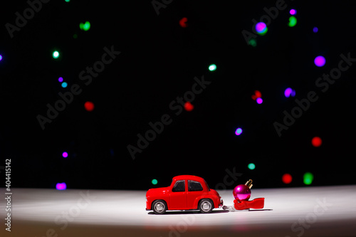 Fototapeta Naklejka Na Ścianę i Meble -  Irkutsk, Russia - November 28, 2020: Christmas red car carrying a sleigh with a christmas ball on christmas eve.