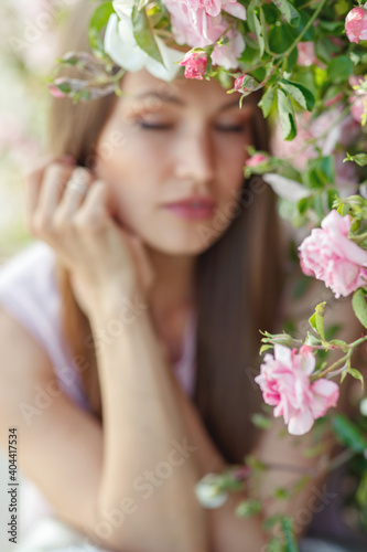 Outdoor photo of a beautiful young woman surrounded by flowers. Spring Flower. Portrait of a girl with roses. High quality photo.