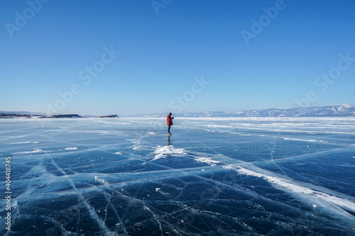 man in winter jacket travel holding camera tripod on frozen Baikal lake in Irkutsk, russia in early February